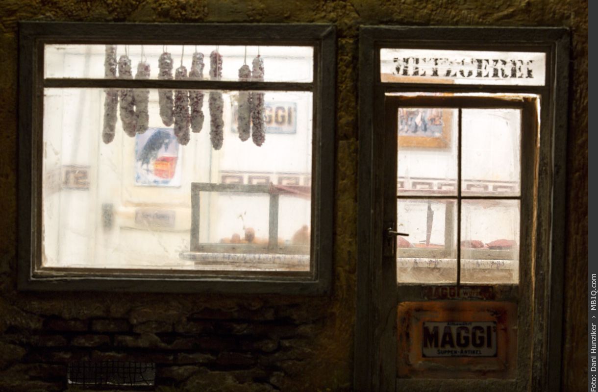 Blick durchs Schaufenster in die beleuchtete Metzgerei