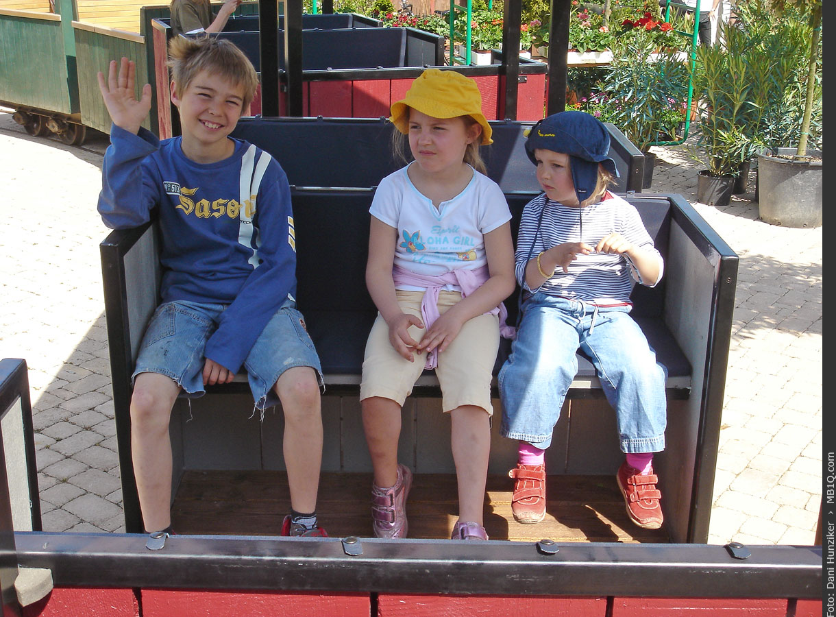 Drei Kinder in einem umgebauten Feldbahnwagen